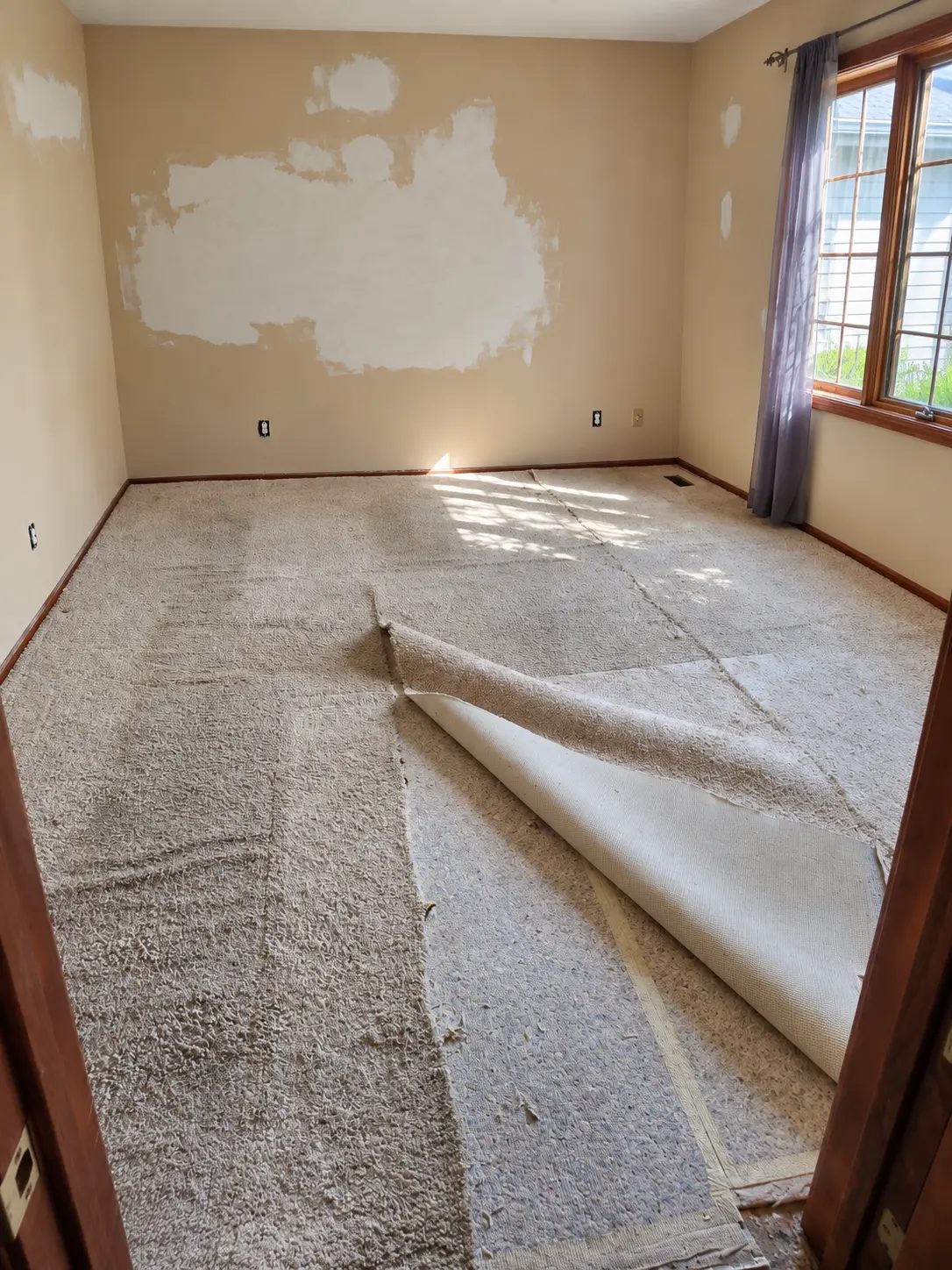 Room before the improvements, with lifted carpet and patched walls