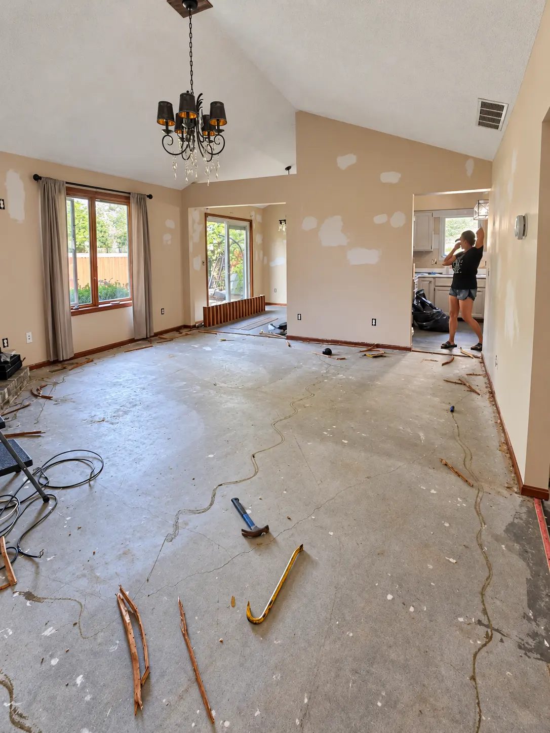 Living area before the improvements, with patched beige walls and exposed subfloor